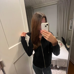 Svart hoodie med dragkedja - Säljer en svart hoodie med dragkedja och långa ärmar. Perfekt för en avslappnad stil och enkel att matcha med olika outfits. Skriv för mer bilder osv 