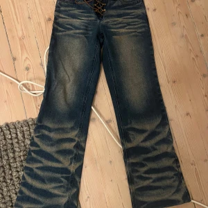 Blå jeans med snörning från Jaded London - Snygga blå jeans från Jaded London med unik snörning framtill och broderade detaljer på bakfickorna. De har en bootcut-stil som ger en cool retrovibe. Perfekta för dig som vill sticka ut!