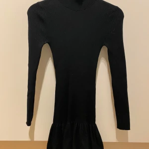 Svart klänning från Zara - Elegant svart klänning från Zara i en tight passform. Klänningen är långärmad och har en ribbad struktur som ger en stilren look. Perfekt för en chic och minimalistisk stil. Klänningen är använd ett fåtal gånger 