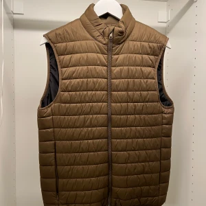 Brun quiltad dunväst från Zara - Säljer en snygg brun quiltad dunväst från Zara. Västen har en dragkedja framtill och är perfekt för lager-på-lager under höst och vår. Den är stilren och lätt att matcha med olika outfits.