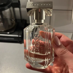 Parfym Hugo Boss The Scent For Her Pure Accord - Elegant parfymflaska från Hugo Boss med en stilren design. Doften är en del av 'The Scent'-kollektionen, känd för sina sofistikerade och förföriska noter. Just denna doft är Hugo Boss The Scent For Her Pure Accord, som ni kan se på bilden. Det är ungefär 1/3 kvar av en 50 ml flaska. Nypris ligger runt 800 kr.