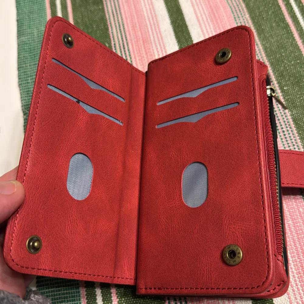 Snygg röd plånbok i syntetmaterial med flera kortfack och en praktisk dragkedja. Den har även en knappstängning och plats för mobiltelefon. Perfekt för att hålla ordning på dina kort och kontanter.iphon 11 PRO.. Laukut & Käsilaukut.