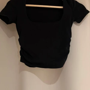 Svart kortärmad topp från Zara - Snygg svart topp från Zara med korta ärmar och en fyrkantig urringning. Perfekt för en stilren look. Tillverkad i ett mjukt material som ger en bekväm passform.