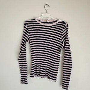 Randig ribbad tröja från H&M - Säljer en randig ribbad tröja från H&M i svart och rosa. Tröjan har långa ärmar och en rund halsringning. Perfekt för en avslappnad stil.