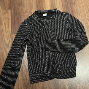 Tröja  - Säljer en svart och silver glittrig tröja från Lindex i storlek 146/152 med långa ärmar. Säljer denna då den har blivit för liten för mig. 