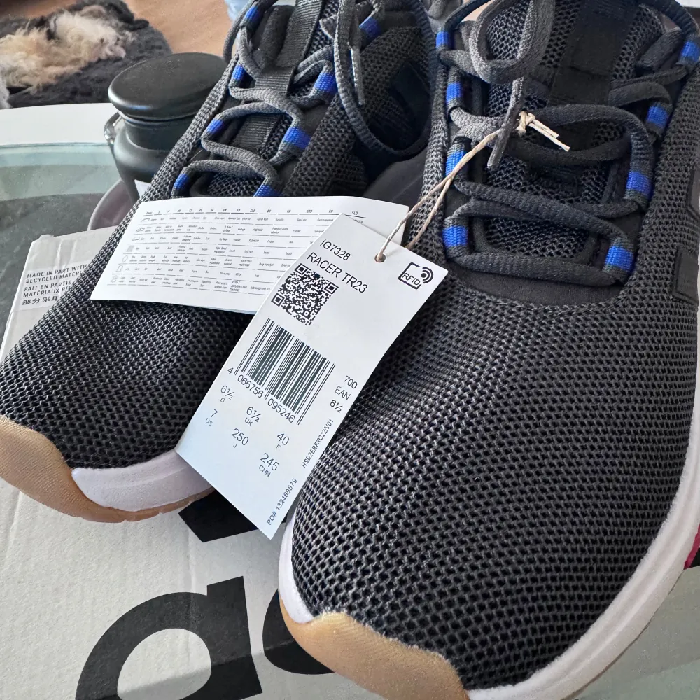 Snygga svarta Adidas sneakers med vita sulor och blå detaljer. Skorna har en modern design med snörning och är perfekta för en sportig look. De har en bekväm passform och är idealiska för vardagsbruk.. Kengät.