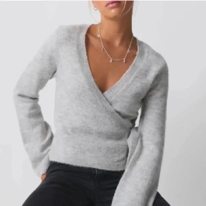 Grå omlottkofta från Gina tricot  - Säljer en stilren grå omlottkofta från Gina Tricot . Koftan har en v-ringad design med knytband i midjan och långa ärmar. Perfekt för en mysig och trendig look. Använd fåtal gånger