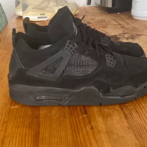 Svarta Nike Air Jordans - Säljer ett par svarta Nike Air Jordans med snörning och ikonisk design. Skorna har en robust sula och detaljer i syntetmaterial. Perfekta för dig som älskar klassiska sneakers med en modern touch.