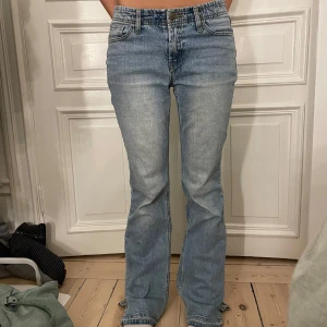 Blå bootcut jeans - Snygga blå bootcut jeans med klassisk femficksdesign och knappgylf. Perfekta för en avslappnad stil med en touch av retro. Passar bra till både sneakers och klackar.
