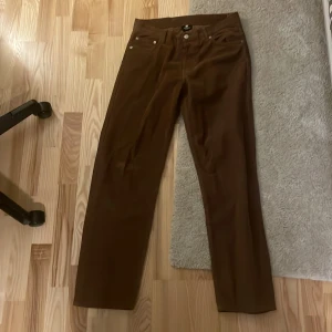 Bruna manchesterbyxor från SWEET SKTBS - Snygga bruna manchesterbyxor från SWEET SKTBS med klassisk design. Byxorna har en rak passform och är perfekta för en avslappnad stil. De har fickor både fram och bak samt en knappstängning i midjan.