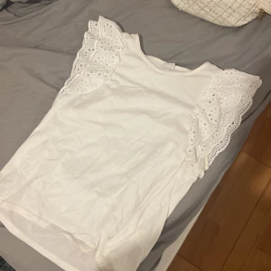  Topp med spets detaliger vid armarna  - Säljer en söt vit topp från Lindex med fina spetsdetaljer på ärmarna. den är i bra skick. är i storlek 146-152 men passar xs🩷