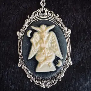 Silverfärgat smycke med vacker medaljong i vintagedesign.  Talismanen avbildar sittande Baphomet, även kallad getguden från Mendez. Medaljongen är 5,8x3,8 cm, kedjan 47. Justerbar längd. Jag prutar inte, ger bundlerabatt. Smycket är nytt och oanvänt.