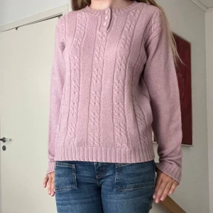Ljusrosa stickad tröja från Northern Isles - Säljer en superfin ljusrosa stickad tröja från Northern Isles. Den är gjord av 70% ull och 30% nylon, vilket gör den både varm och hållbar. Tröjan har ett snyggt flätmönster på framsidan och tre knappar vid halsen. Perfekt för höst och vinter! 💖