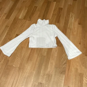 Vit tröja med krage och utsvängda armar. - Använd en gång, som ny.