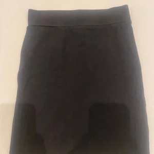 Svart kjol - Säljer en enkel och stilren svart kjol. Den är perfekt för både vardag och fest. Kjolen har en normal passform och är gjord av ett mjukt och bekvämt material. Den är knälång och har en slät yta utan några extra detaljer.