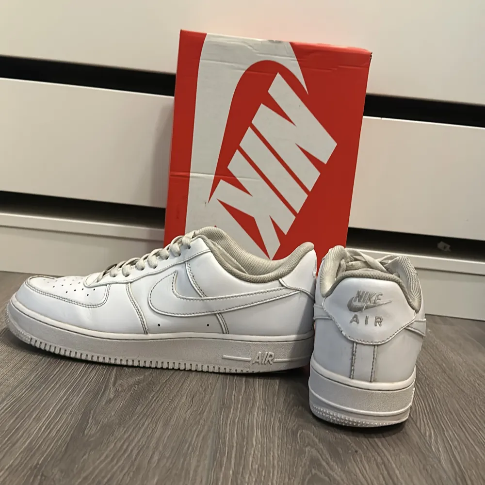 Säljer ett par vita Nike Air Force 1 sneakers i storlek 45. Skorna är i bra skick med klassisk design och bekväm passform. Perfekta för vardagsbruk eller träning. Levereras med originalkartong. Skriv dm för fler funderingar.. Skor.