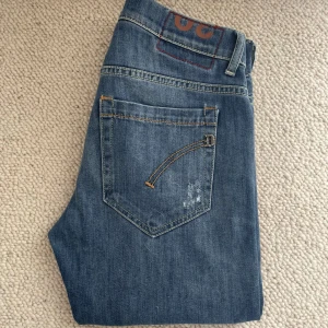 Blå jeans Dondups - Säljer ett par snygga Dondup jeans i storlek W30. De har en straight passform och är tillverkade i slitstarkt jeansmaterial. Jeansen har en klassisk femficksdesign med en knapp och dragkedja framtill. Använda men i toppskick! Skicka dm vid frågor. 