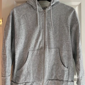 Grå hoodie från 157 - Säljer en grå hoodie från 157 i storlek S. Den är supermjuk och bekväm, perfekt för vardagsbruk. Hoodien har en dragkedja framtill och två fickor. Den har också en justerbar huva med snören. Perfekt för höst och vinter!