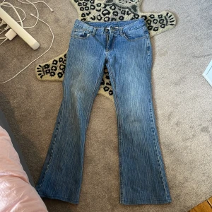 Blå bootcut jeans - Säljer ett par snygga blå low waist bootcut jeans. De är i bra skick och har en klassisk femficksdesign med dragkedja och knapp framtill. Perfekta för både vardag och fest! Säljs då de är för stora.🩷Från brandy mellville! TRYCK INTE “KÖP NU”