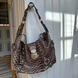 Brun guess väska - Vintage, stor, ormskinn, på andra bilden ser man att magneten på guessloggan saknas, men man kan limma på/skruva på en sån själv! Väskan har en dragkedja så den går ändå att stänga 💖