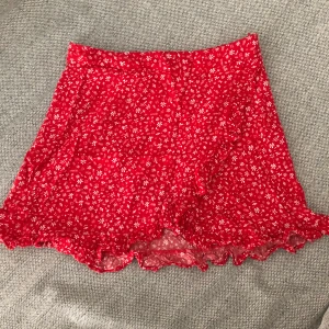 Sommarkjol - Kort sommarkjol i rött med små vita blommor på. 