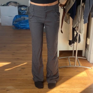 Lågmidjade grå randiga kostymbyxor  - Lågmidjade grå randiga kostymbyxor  Rakt över midjan: 39 Innerben: 84 