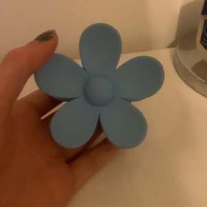 Blå hårklämma i form av en blomma - Säljer en superfin blå hårklämma formad som en blomma. Perfekt för att hålla håret på plats med stil. Klämman är gjord av plast och har en stark fjäder som håller den på plats hela dagen. Passar både till vardags och fest!