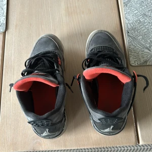 Gråa Nike Air Jordans med röda detaljer - Säljer ett par gråa Nike Air Jordans med röda detaljer. Skorna är i välanvänt skick men fortfarande snygga och bekväma. De har svarta snören och en cool design med mesh-detaljer på sidorna. Perfekta för både vardag och fest!