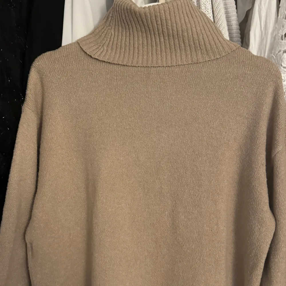Mysig beige stickad polotröja med ribbad krage. Perfekt för kyliga dagar och ger en stilren look. Passar bra till både jeans och kjol. Den är trekvartsärmad!. Neuletakit & Villapaidat.