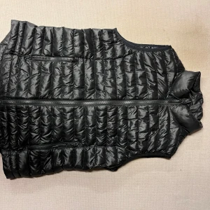 Svart väst från Everest - Snygg svart väst från Everest med dragkedja framtill. Perfekt för lager-på-lager under kyliga dagar. Västen har en stilren design och är lätt att matcha med olika outfits.