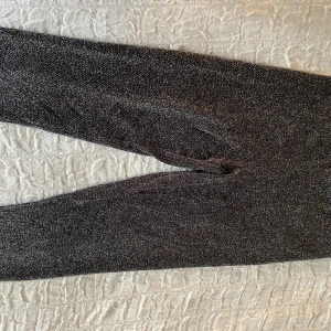 Glittriga byxor och topp från Gina Tricot - Snygga glittriga byxor och matchande topp från Gina Tricot i storlek XS. Perfekt för en festlig look med sitt glittriga mönster och stilrena design. Byxorna har en tight passform och toppen har tunna axelband. Toppen har långa axelband som inte går att reglera därav rekommenderar jag settet till en person med större byst. 