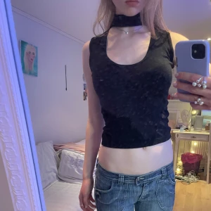 Svart ärmlös topp - Snygg svart ärmlös topp med hög halsringning. Perfekt för en stilren look.