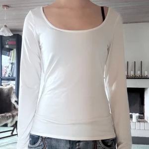 Vit långärmad topp - Säljer en stilren vit långärmad topp med rund halsringning. Perfekt för en enkel och klassisk look. Passar bra till jeans eller kjol.