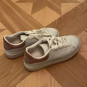 Sneakers Alexander McQueen - Snygga vita sneakers med rosa detaljer från Alexander McQueen. De är i använt skick men ser bra ut! Storlek står ej men skulle säga 38.