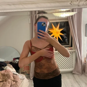 Brun blommig linne - Säljer ett brunt linne med blommigt mönster och smala axelband. Perfekt för en somrig look eller att bära under en kavaj. Passar bra till både jeans och kjol.