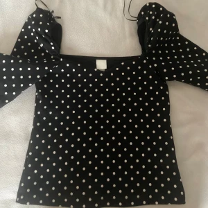 Svart prickig topp från H&M - Säljer en svart topp med vita prickar från H&M. Toppen har en fyrkantig halsringning. Perfekt för en stilren look med en touch av retro. Passar bra till både jeans och kjol. 