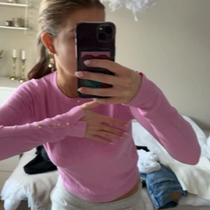 Rosa tröja med knappar - Säljer en söt rosa tröja med långa ärmar och dekorativa knappar vid ärmsluten. Super skönt material och med en mudd längst ner. Köpt på zara