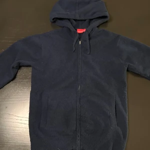 Cashmere hoodie  - Säljer en mörkblå hoodie från RYVLS med dragkedja och huva. Perfekt för kyliga dagar med sin mjuka och bekväma design. Den har praktiska fickor framtill och justerbara snören vid huvan. Passar någon som är 160cm