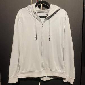 Säljer en stilren ljusgrå hoodie från Brave Soul. Den har en dragkedja framtill och justerbar huva med snören. Perfekt för en avslappnad look. Det är en unik färg, ljusblå men med mer nyans åt vitt än blå 