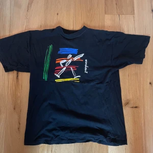 Svart t-shirt med färgglatt tryck - Snygg svart t-shirt köpt från second hand. Ganska stor passform.