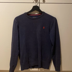Mörkblå tröja från Polo Ralph Lauren - Säljer en stilren mörkblå tröja från Polo Ralph Lauren i mjuk pima bomull. Tröjan har en klassisk design med långärmad passform och det ikoniska röda broderade logotypen på tröjan. Tröjan är i ny skick och köptes för 1 år sen på mellan dags rean för 869kr. Men började använda den i sommras och säljer nu på grund av att den är för liten.. Tröjan är i storlek 14-16 år/L barnstorlek men skulle säga att den passar runt 150/M. Hör av er om ni har några frågor eller prisförslag. 