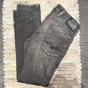 Replay Jeans Anbass Grå - Snygga grå jeans från Replay, modell Anbass. De har en klassisk femficksdesign med dragkedja och knapp. Perfekta för en stilren look. Köparen står för frakten!