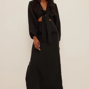 Svart långklänning i linne - Från NA-KD. Slutsåld sen ett tag. 52 % linne. Så så fin. Går att knyta in bandet (se min bild) eller låta det hänga (se första bilderna). Superbra skick, inga defekter och endast använd ett fåtal gånger. Ursprungspris: 699kr