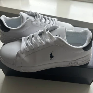 Vita sneakers från Polo Ralph Lauren - Snygga vita sneakers från Polo Ralph Lauren. Skorna har snörning och kommer med extra skosnören. Storlek 42. Snygga o stilrena!! Endast använda en gång innomhus. Nyskick förutom en liten defekt på yttersidan (se sista bild)! Köpta för 1499, säljer för mindre än halva!! 