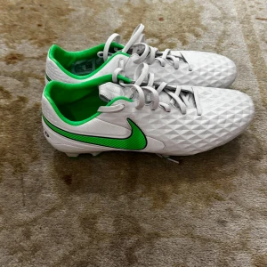 Vita och gröna Nike tiempos - Snygga vita tiempos från Nike. Skorna är i otroligt ba skick använda 1 gång. Skorna är för både konstgräs och vanligt gräs 