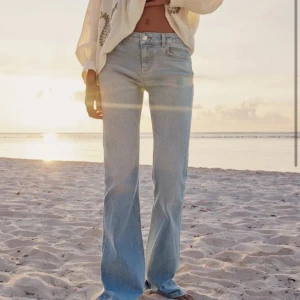 Ljusblå jeans från Zara - Snygga ljusblå jeans från Zara med en klassisk design. De har en rak passform med utsvängda ben längst ner och är perfekta för en avslappnad stil. Jeansen har en dragkedja och knapp framtill.