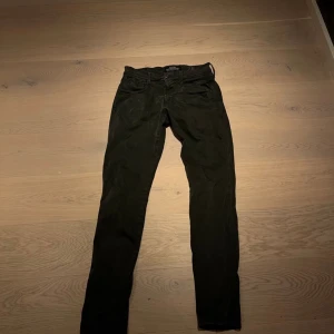 Grå jeansbyxor från Replay - Snygga svarta jeansbyxor från Replay i modellen Anbass. De har en klassisk design med dragkedja och knapp framtill. Perfekta för en stilren look.