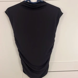 Grå/svart tröja med drapering - Elegant svart/grå tröja från Gina Tricot med draperade detaljer på sidan. Perfekt för en stilren look. Väldigt skön och sitter tight men fint!