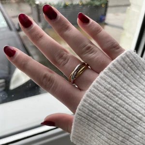 Trippelring i guld och silver - Elegant trippelring med tre sammanflätade band i guld och silver. Perfekt för en stilren och modern look. Passar till både vardag och speciella tillfällen.