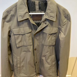 Grön jacka från Massimo Dutti - Snygg grön jacka från Massimo Dutti med knappar och dragkedja. Perfekt för kyliga dagarna men även fram mot våren. Storlek M men funkar även för S. Nypris runt 1100 men de går att diskuteras.